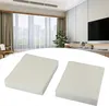 Two white rectangular filters are placed on a white surface in front of a blurred background of a modern room with curtains and a TV. Produktbild-Vorschau