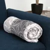A rolled-up blanket with a gray and white pattern is placed on a blue sofa. Produktbild-Vorschau