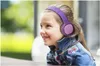 A young girl wearing headphones and a denim jacket, smiling. Produktbild-Vorschau