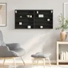 A black wall shelf unit filled with various small items, positioned above a gray armchair and ottoman in a room. Produktbild-Vorschau