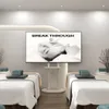 A spa or treatment room with two massage beds and a large TV screen displaying a promotional image. Anteprima dell’immagine prodotto