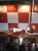 A copper pot and ladle are on a stove in front of a red and white checkered backsplash. Produktbild-Vorschau