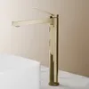 A close-up shot of a modern gold faucet positioned next to a white sink on a marble countertop. Voir les images du produit