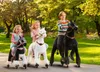 Three children riding toy horses in a park. Anteprima dell’immagine prodotto
