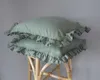 Two mint-colored pillows with ruffles are stacked on a bamboo stool. Produktbild-Vorschau