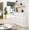 A brightly lit room featuring a white dresser with six drawers, a tall green plant in a pot, and a round coffee table with books and a bowl. Produktbild-Vorschau