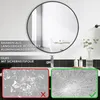 A round black framed mirror is shown above a bathroom sink. Below the sink are two comparison images of broken glass, one with a red cross and one with a green checkmark. Produktbild-Vorschau