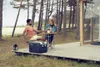 A couple enjoying drinks on a wooden deck outside a cabin, with a Dometic cooler box nearby. Produktbild-Vorschau
