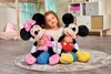 A young girl is sitting on a rug, holding two large plush toys, Minnie Mouse and Mickey Mouse. The background shows a child's room with furniture and decorations. Náhled obrázku produktu