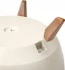 A close-up view of the bottom of a white planter pot with three brown legs attached. Náhled obrázku produktu