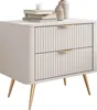 A beige nightstand with two drawers and gold metal legs, decorated with books and vases on top. Náhled obrázku produktu