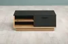 A modern TV stand with a black top and drawer, and light wood shelving and base, is shown in a room with light wood flooring and a blue wall. Voir les images du produit