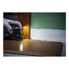 A gloved hand is using a power tool to cut into a wooden door frame near the floor. Voir les images du produit