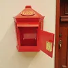 A red retro post box mounted on a wall next to a wooden door. Produktbild-Vorschau