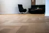 A living room scene with a herringbone floor, a black armchair, and a black sofa. Produktbild-Vorschau