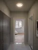 A hallway with a ceiling light, a door leading to another room, and a wall of cabinets. Produktbild-Vorschau