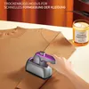 A person is using a portable handheld steamer on a brown knitted garment. A candle is visible in the background. Produktbild-Vorschau
