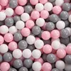 A close-up view of a pile of small, round balls in white, gray, and pink colors. Produktbild-Vorschau