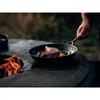 A person is cooking steak in a pan over an open fire. Produktbild-Vorschau