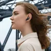 A woman wearing wireless earbuds, with a bridge structure in the background. Anteprima dell’immagine prodotto