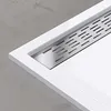 A close-up view of a white shower tray with a silver drain. Produktbild-Vorschau