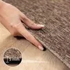 A hand is shown pressing down on a brown carpet, with a close-up inset showing the carpet's thickness. Náhled obrázku produktu