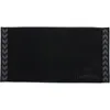 A black towel with grey chevron patterns on the sides and a grey logo and brand name on the bottom right. Produktbild-Vorschau