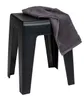A black plastic stool with a gray towel draped over it, isolated on a white background. Produktbild-Vorschau