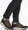 A person wearing black jeans and brown Rieker sneakers. Voir les images du produit