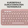 A close-up view of a pink Logitech keyboard with German text overlay. Produktbild-Vorschau