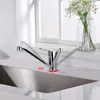 A chrome kitchen faucet is shown above a stainless steel sink, with a vase of white flowers in the background. Produktbild-Vorschau
