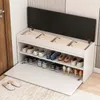 A white shoe cabinet with a black lid, open to reveal shelves with shoes and folded items. Podgląd zdjęcia produktu