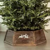 A Christmas tree with lights and a wooden tree skirt decorated with reindeer and the words "Merry Christmas". Voir les images du produit
