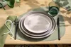 A table setting with plates, cutlery, a napkin, and a glass of water. Produktbild-Vorschau