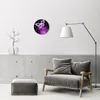 A modern living room with a gray armchair and ottoman, a floor lamp, and a wall clock with a butterfly design. Produktbild-Vorschau