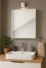 A modern bathroom sink area with a mirror, faucet, soap dispenser, toothbrush holder, and a plant. Produktbild-Vorschau