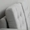 Close-up view of the tufted backrest and armrest of a light gray sofa. Náhled obrázku produktu
