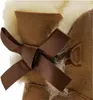 A close-up view of a brown Ugg boot with a brown ribbon bow and cream-colored lining. Produktbild-Vorschau