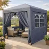 A pop-up gazebo set up on a patio with two chairs and a small table inside. Produktbild-Vorschau