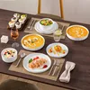A beautifully set dining table with various dishes, including soup, salad, pasta, dessert, and cupcakes, arranged on placemats with cutlery and a glass of wine. Produktbild-Vorschau