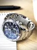 A silver Casio Edifice watch with a blue face rests on a wooden surface next to a notebook and pen. Podgląd zdjęcia produktu