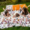 Three children are lying on a bed with a floral and bird-patterned duvet cover outdoors on the grass. Produktbild-Vorschau