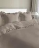 A neatly made bed with taupe bedding and ruffled edges. Produktbild-Vorschau