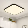 A square LED ceiling light with a black frame is mounted on a white ceiling above white kitchen cabinets. Voir les images du produit