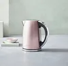A pink Cuisinart electric kettle is displayed on a light gray surface with a light blue-green textured background. A small pink bowl and a gold spoon are to the left of the kettle. Voir les images du produit