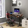 A gaming setup with an adjustable desk, computer, and chair in a room. Produktbild-Vorschau