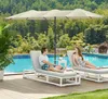 A couple relaxing on lounge chairs under a large umbrella next to a swimming pool. Produktbild-Vorschau