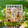 A miniature greenhouse model surrounded by moss and flowers, with a reflection in the water below. Anteprima dell’immagine prodotto