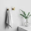 A bathroom setting with two gold hooks on a white wall, one holding a white towel. A vase with green eucalyptus branches is on a marble countertop to the right. Anteprima dell’immagine prodotto
