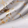 A close-up view of a grey fabric with a gold marbled pattern. Produktbild-Vorschau